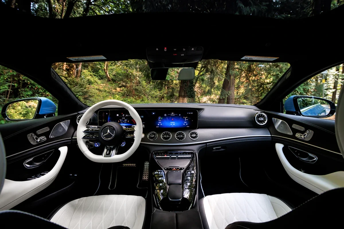 Luxury sedan interior from the rear seat: dashboard, windshield and front side windows looking out on a forest